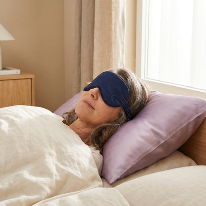 Woman wearing Walo Halo navy silk sleep mask in bed